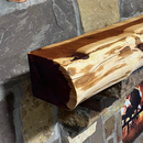 A live edge style fireplace mantel, made from cedar wood, mounted on a stone wall.
