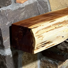 A live edge style fireplace mantel, made from cedar wood, mounted on a stone wall.
