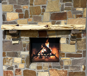 A live edge style fireplace mantel, made from cedar wood, mounted on a stone wall.
