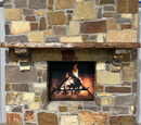 A live edge style fireplace mantel, made from cherry wood, mounted on a stone wall.