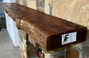 A live edge style fireplace mantel, made from cherry wood, mounted on a stone wall.