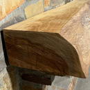 A live edge style fireplace mantel, made from pecan wood, mounted on a stone wall.