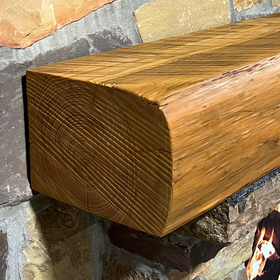 A live edge style fireplace mantel, made from pine wood, mounted on a stone wall.
