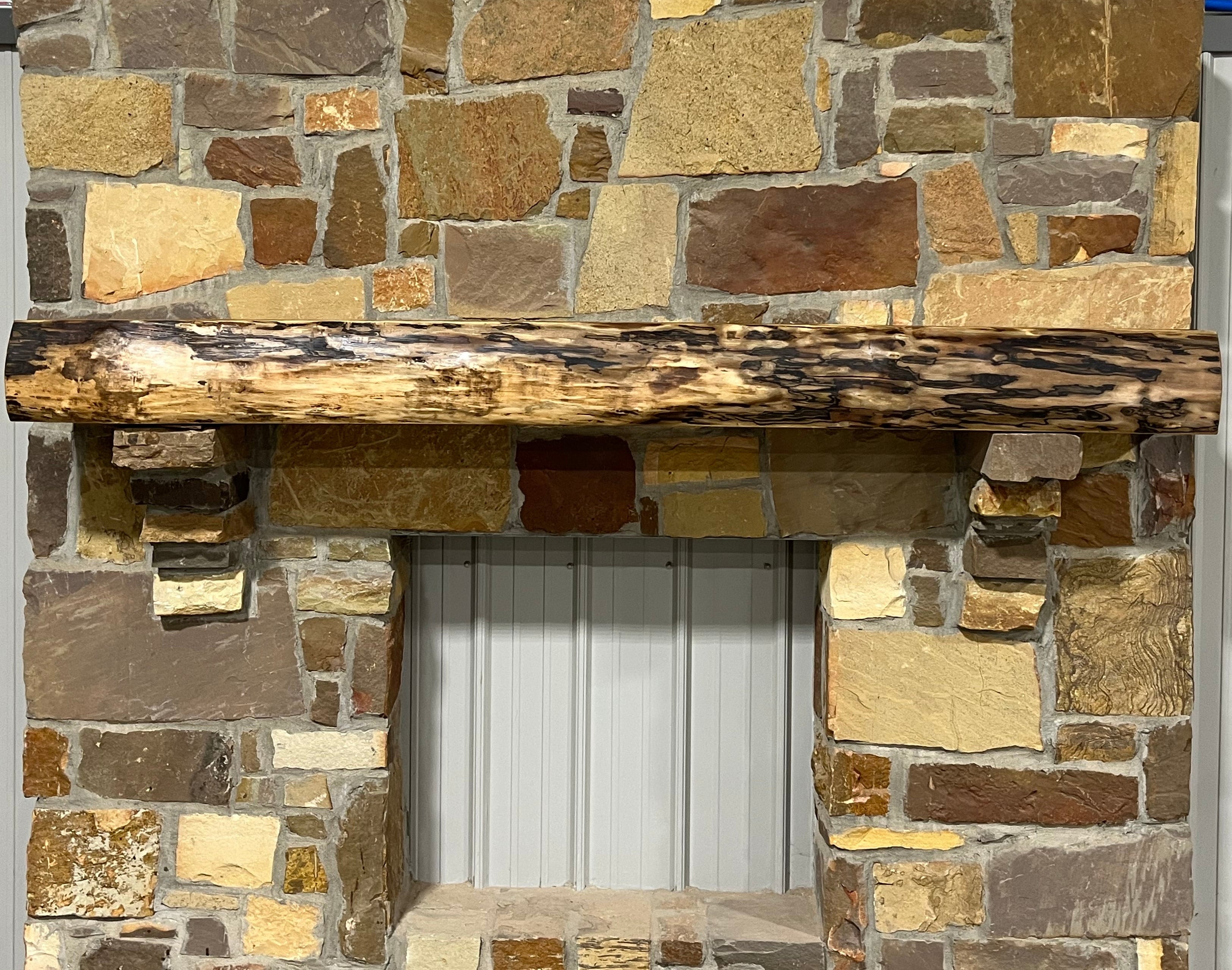 Solid live edge walnut fireplace mantel mounted on a stone wall.