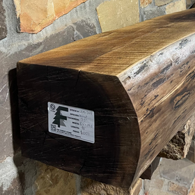 A live edge style fireplace mantel, made from walnut wood, mounted to a rock wall.
