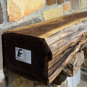 A live edge style fireplace mantel, made from walnut wood, mounted to a rock wall.