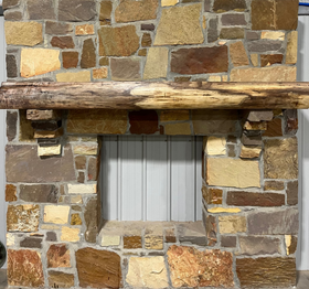 A live edge style fireplace mantel, made from walnut wood, mounted to a rock wall.