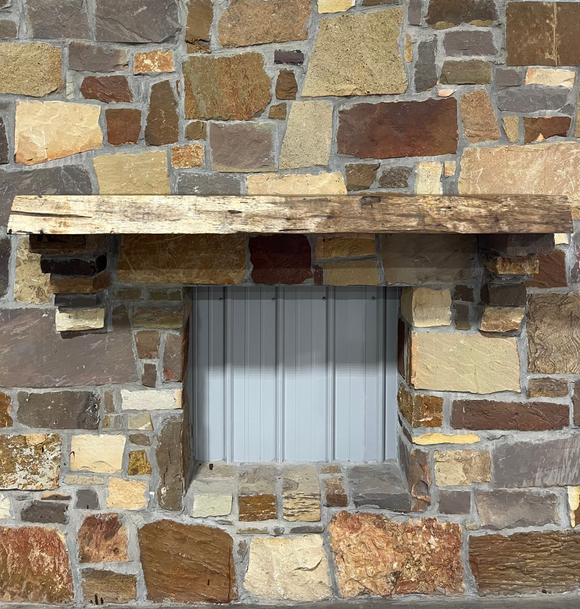 A live edge style fireplace mantel, made from walnut wood, mounted to a rock wall.