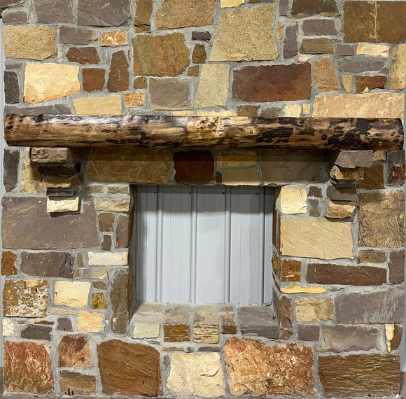 A live edge style fireplace mantel, made from walnut wood, mounted to a rock wall.