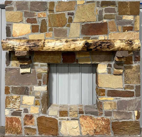 A live edge style fireplace mantel, made from walnut wood, mounted to a rock wall.