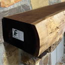 A live edge style fireplace mantel, made from walnut wood, mounted to a rock wall.