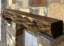 A live edge style fireplace mantel, made from walnut wood, mounted to a rock wall.