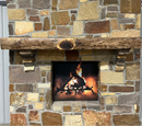 A live edge style fireplace mantel, made from walnut wood, mounted to a rock wall.