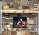 A live edge style fireplace mantel, made from walnut wood, mounted to a rock wall.