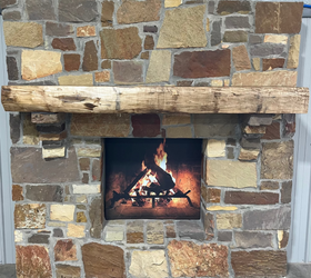 A live edge style fireplace mantel, made from walnut wood, mounted to a rock wall.