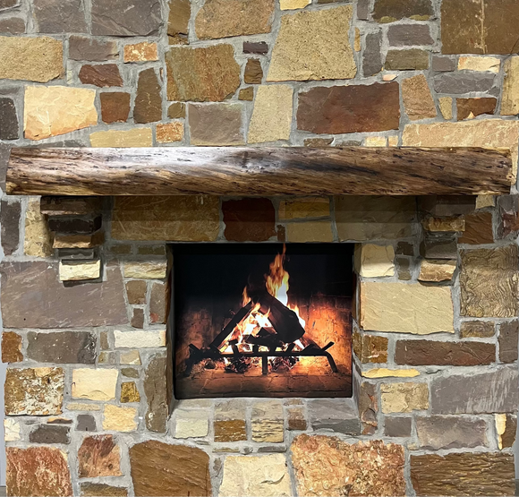 A live edge style fireplace mantel, made from walnut wood, mounted to a rock wall.