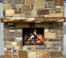 A live edge style fireplace mantel, made from walnut wood, mounted to a rock wall.