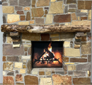 A live edge style fireplace mantel, made from walnut wood, mounted to a rock wall.