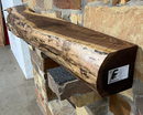 A live edge style fireplace mantel, made from walnut wood, mounted to a rock wall.