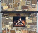 A live edge style fireplace mantel, made from walnut wood, mounted to a rock wall.