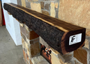 A live edge style fireplace mantel, made from walnut wood, mounted to a rock wall.