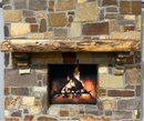 A live edge style fireplace mantel, made from walnut wood, mounted to a rock wall.