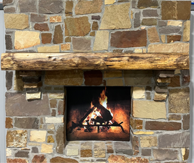 A live edge style fireplace mantel, made from walnut wood, mounted to a rock wall.