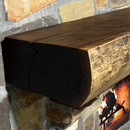 A live edge style fireplace mantel, made from walnut wood, mounted to a rock wall.