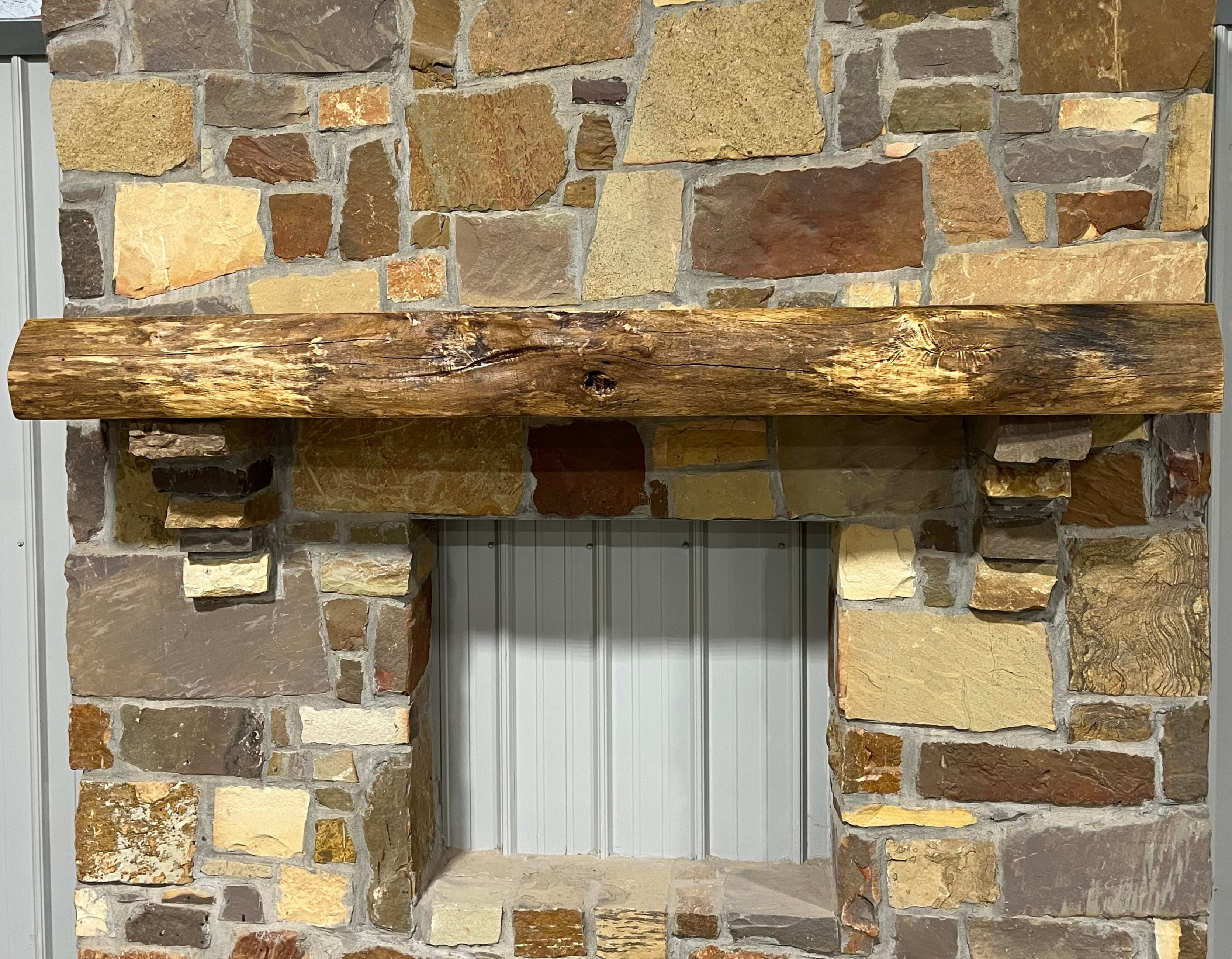 Live edge white oak fireplace mantel with natural grain and rustic finish mounted on a stone wall.