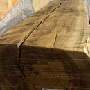 A live edge style fireplace mantel, made from white oak wood, mounted on a stone wall.