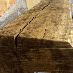 A live edge style fireplace mantel, made from white oak wood, mounted on a stone wall.