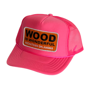 A hot pink trucker hat with a Wood is Wonderful Hochatown Oklahoma patch