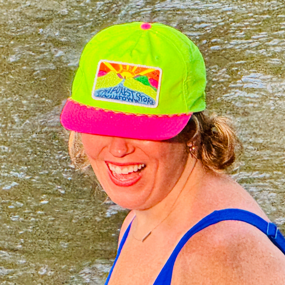 Person wearing a colorful neon The Forest Store Hochatown - Life is a Gift hat standing in water.