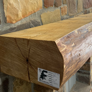 Solid live edge ash fireplace mantel mounted on a stone wall.