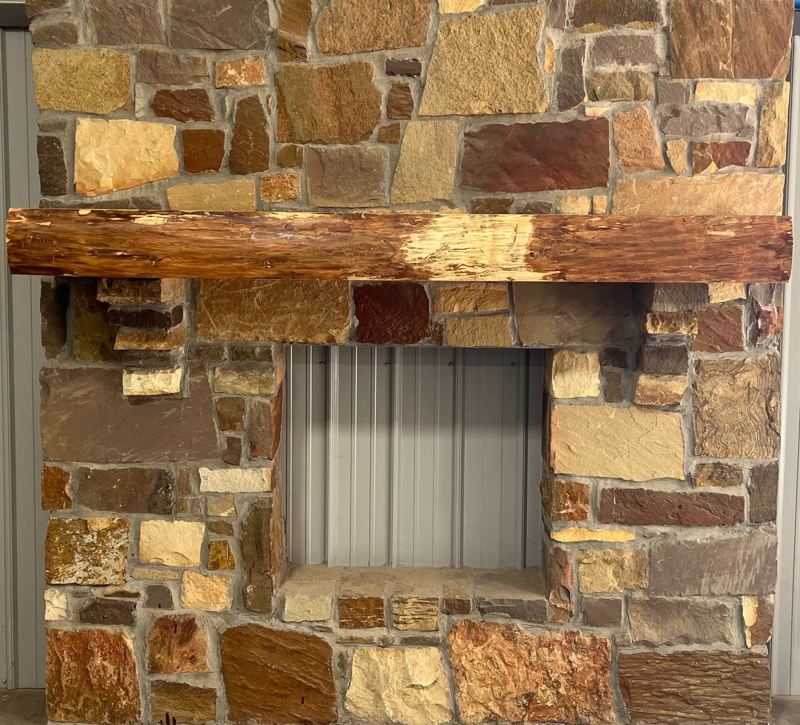 Solid live edge ash fireplace mantel mounted on a stone wall.
