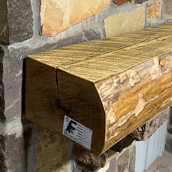 Solid live edge ash fireplace mantel mounted on a stone wall.