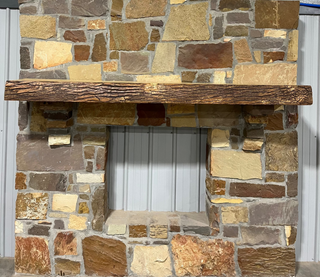 Solid live edge ash fireplace mantel mounted on a stone wall.