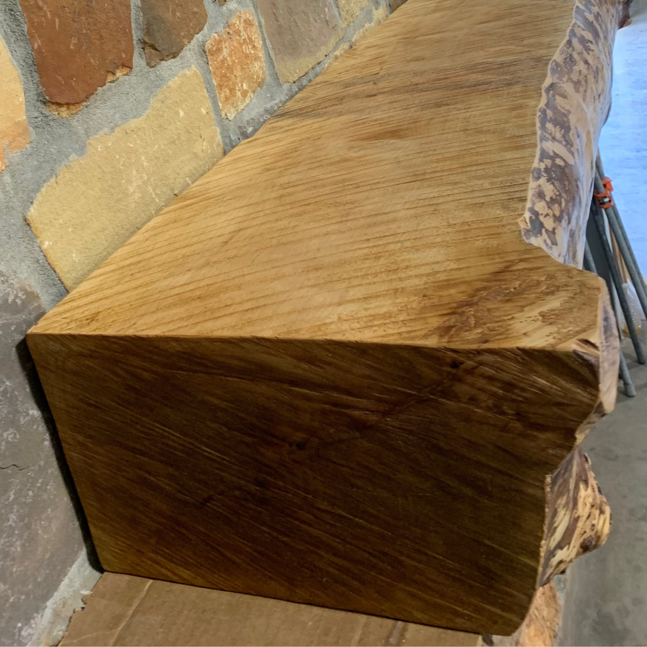 Solid live edge birch fireplace mantel mounted on a stone wall