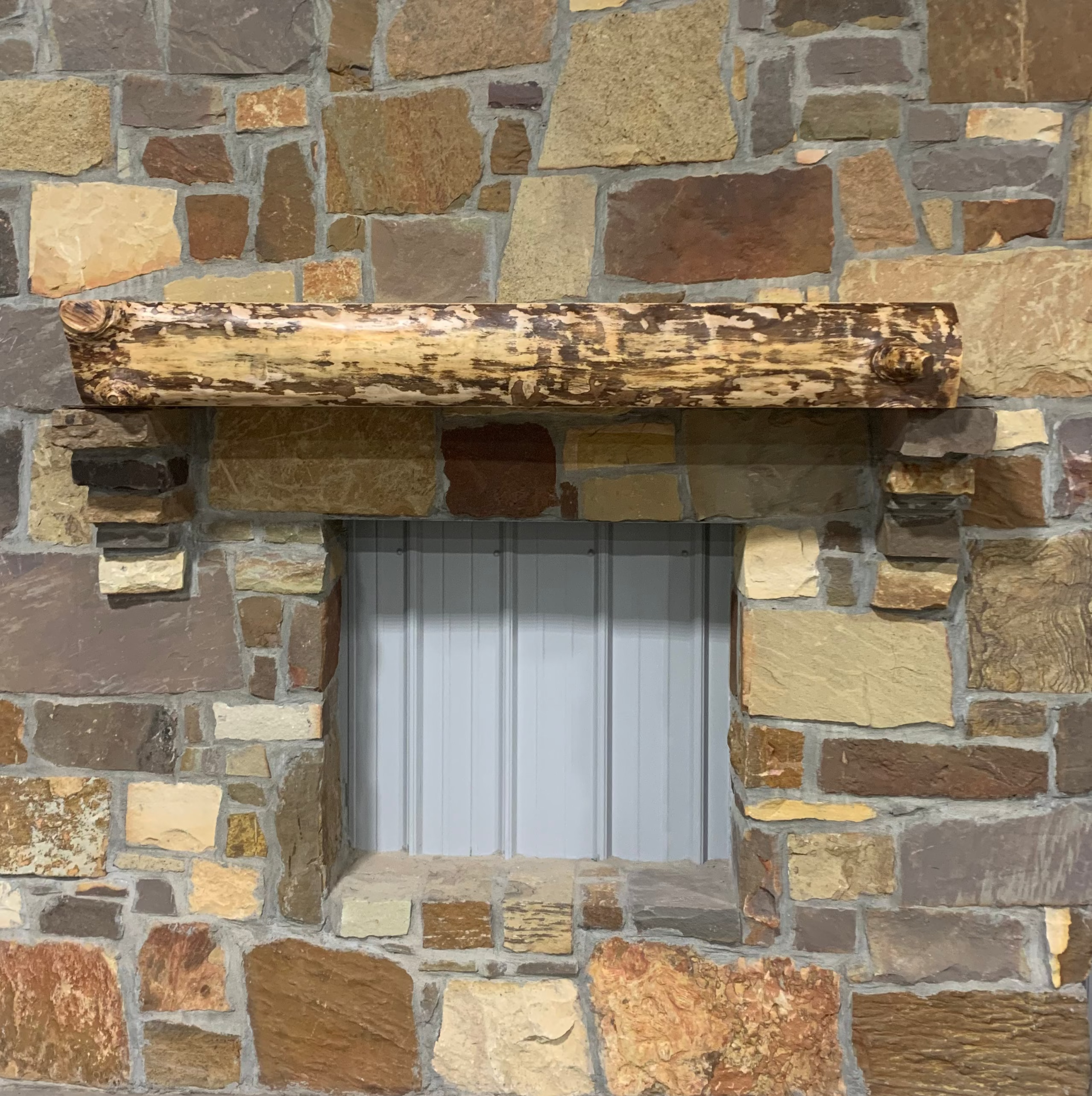 Solid live edge birch fireplace mantel mounted on a stone wall