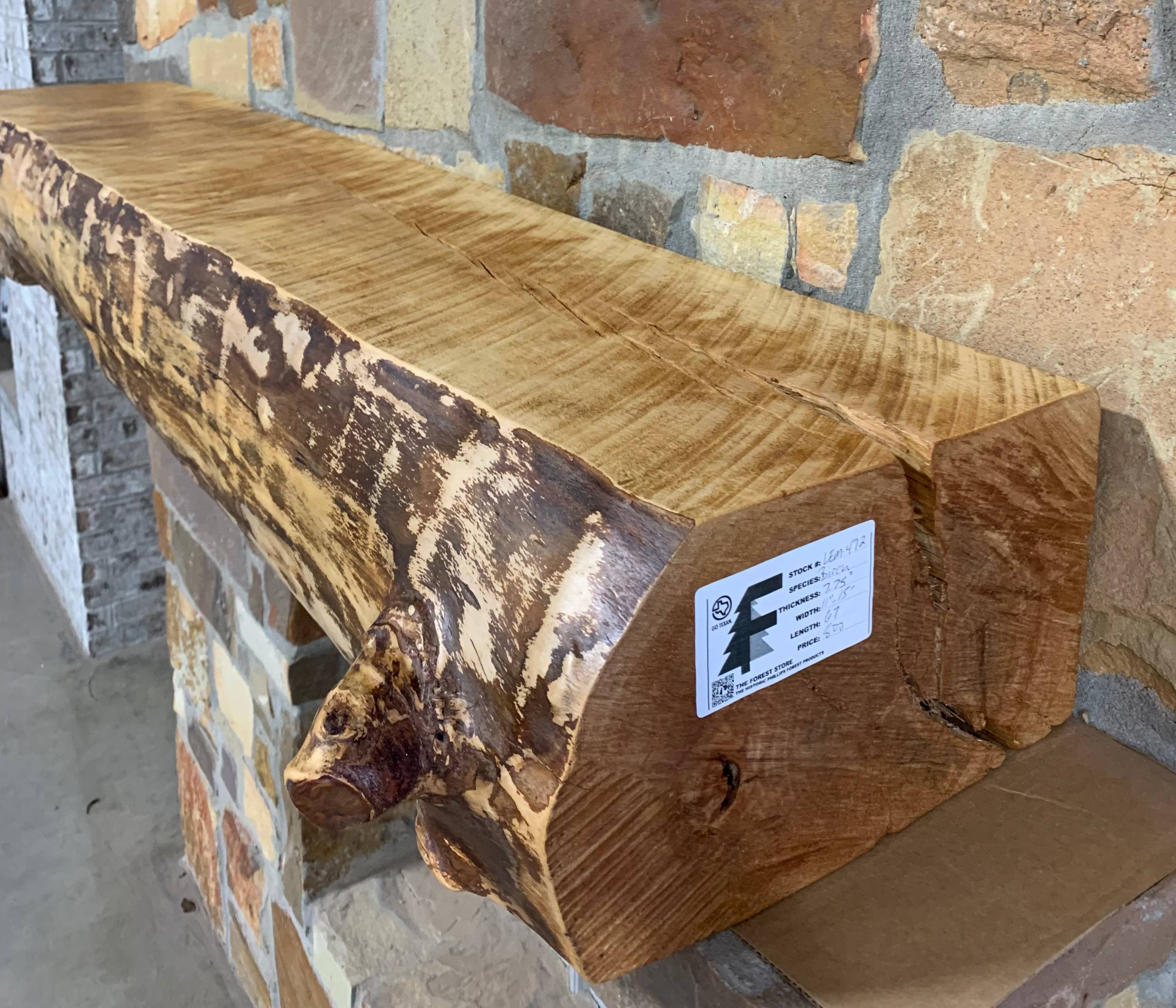 Solid live edge birch fireplace mantel mounted on a stone wall
