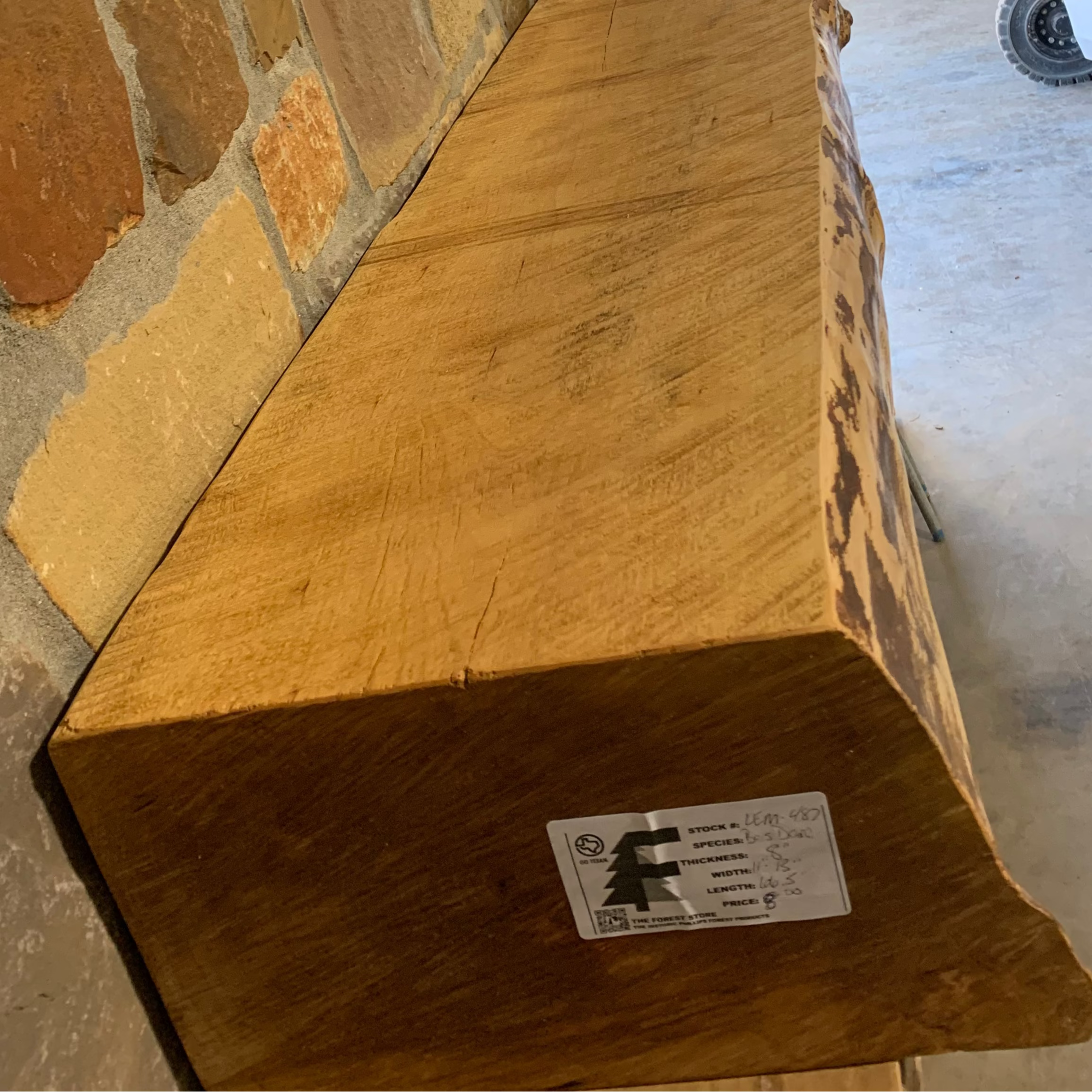 Solid live edge birch fireplace mantel mounted on a stone wall