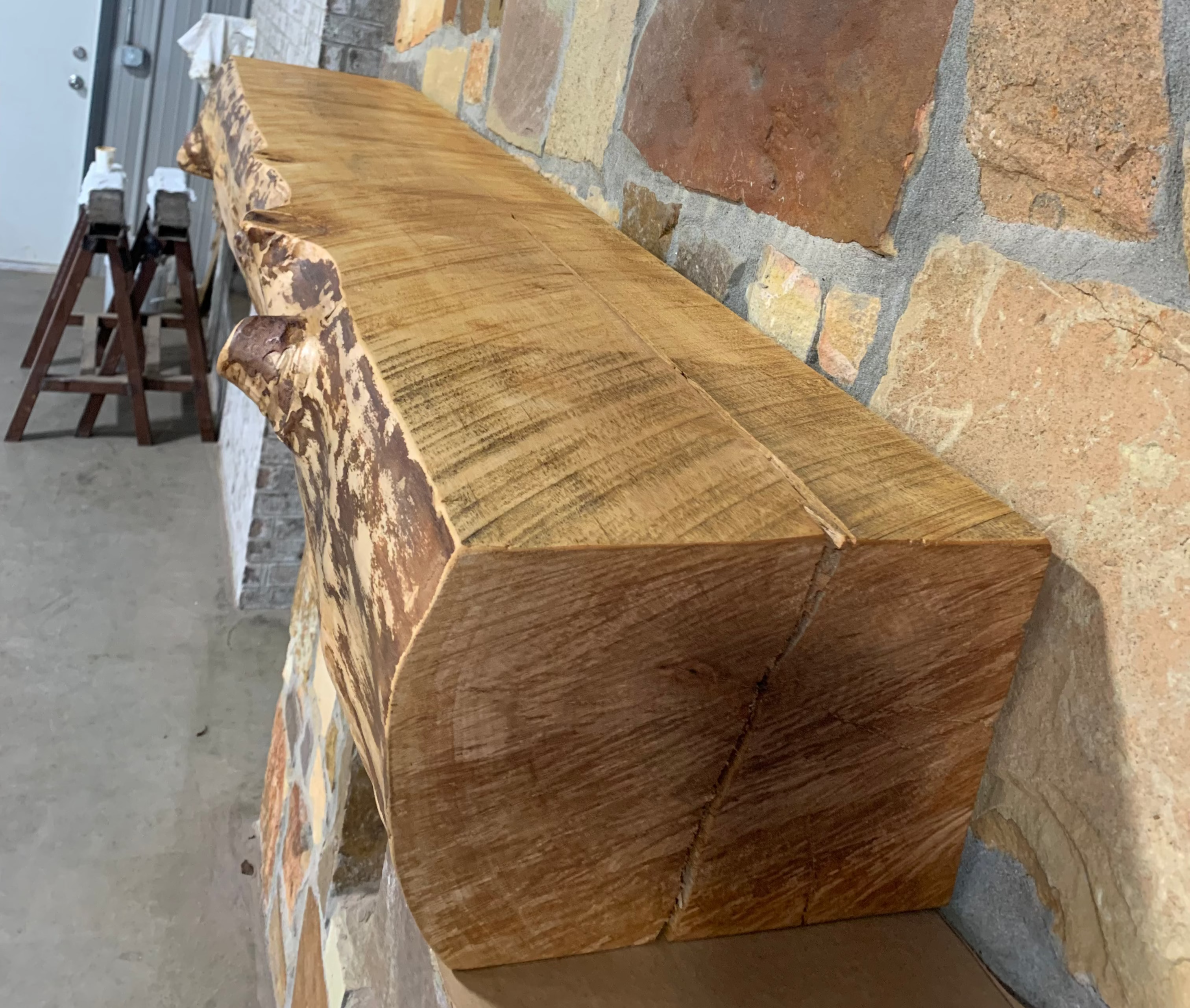 Solid live edge birch fireplace mantel mounted on a stone wall