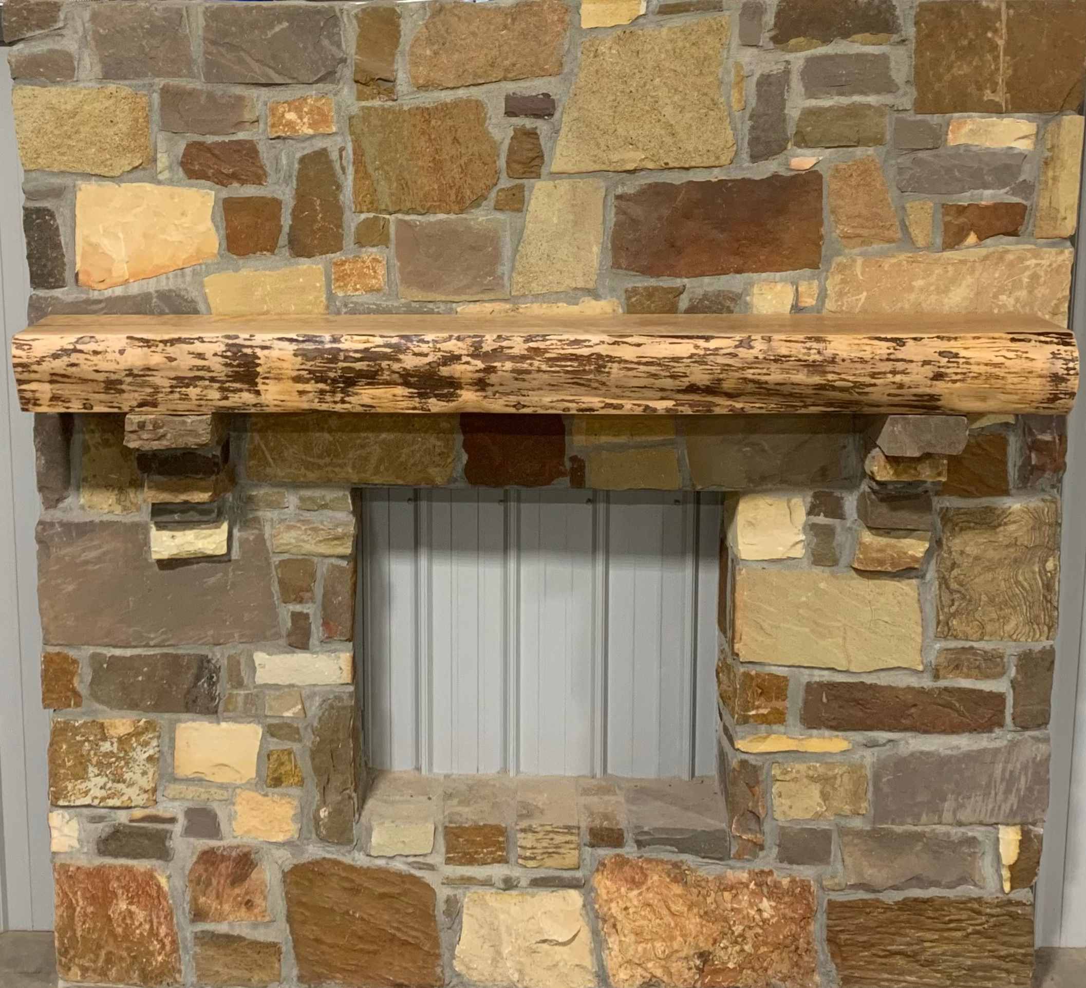 Solid live edge birch fireplace mantel mounted on a stone wall