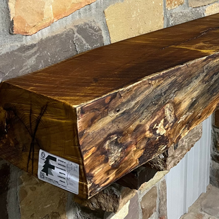 Solid live edge bois d'arc fireplace mantel mounted on a stone wall.
