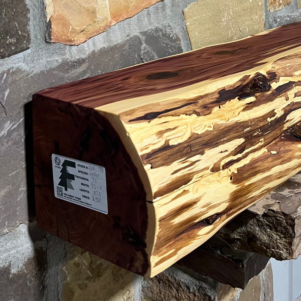 Solid live edge cedar fireplace mantel mounted on a stone wall.