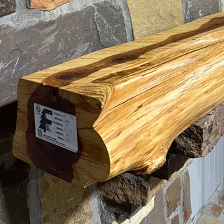 Solid live edge cedar fireplace mantel mounted on a stone wall.