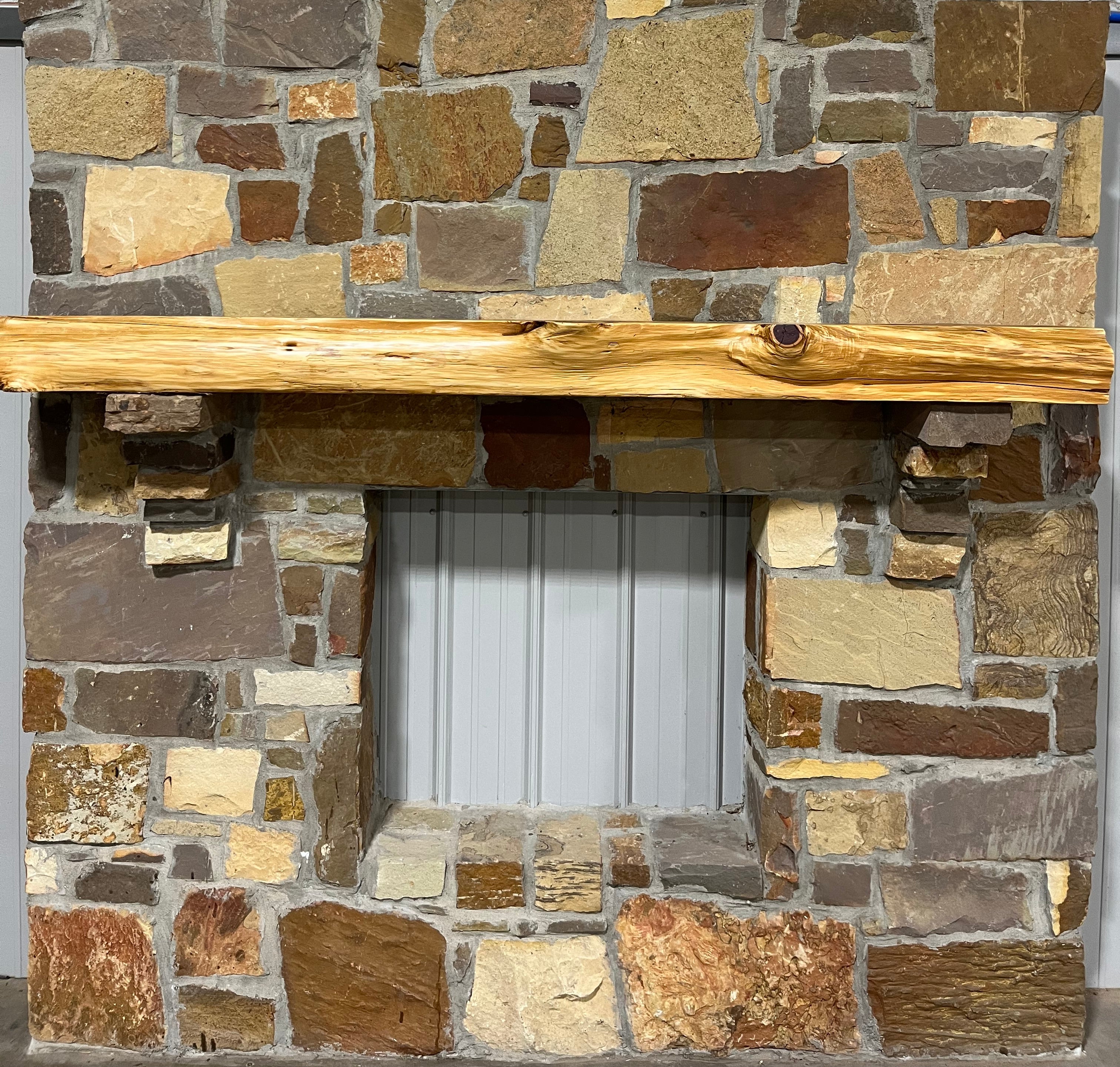 Solid live edge cedar fireplace mantel mounted on a stone wall.