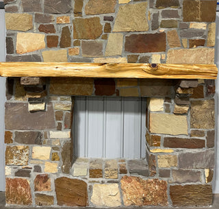 Solid live edge cedar fireplace mantel mounted on a stone wall.