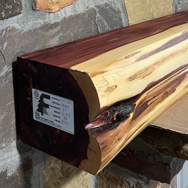 Solid live edge cedar fireplace mantel mounted on a stone wall.
