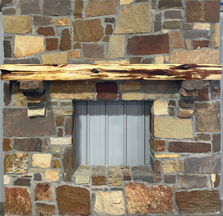 Solid live edge cedar fireplace mantel mounted on a stone wall.
